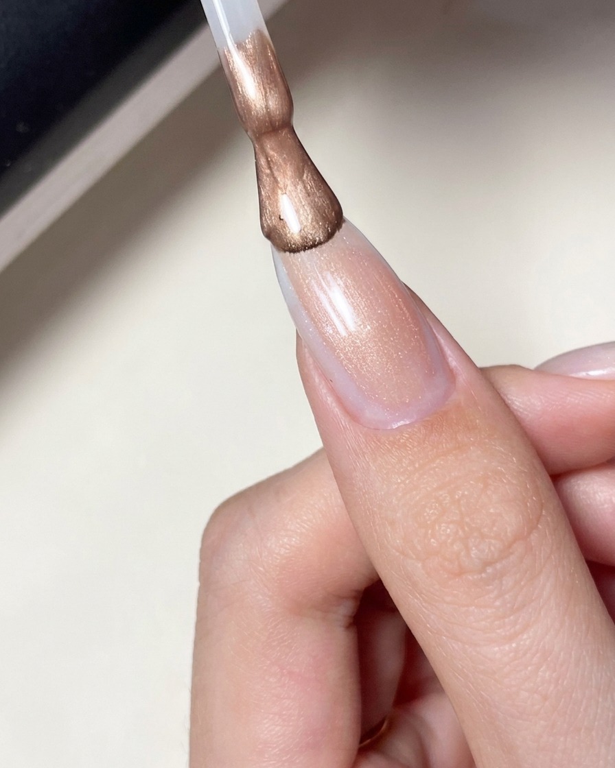 별 디자인이 들어간 손톱 위에 밀키한 핑크 시어 젤 폴리시를 붓으로 바르는 모습.