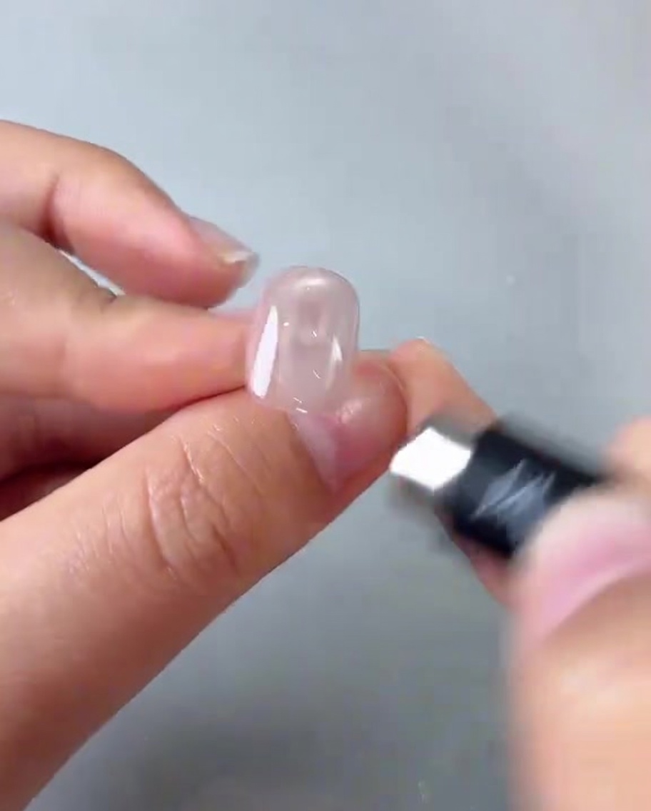 원통형 자석을 핑크 젤 네일 위에서 움직여 가운데 밝은 반사광을 만드는 모습.