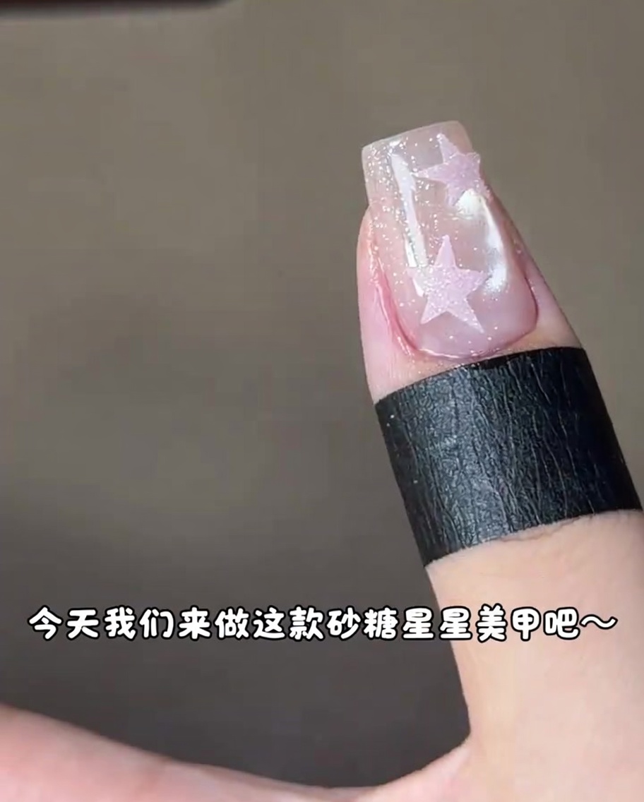 UV 네일 램프 아래에서 핑크 별 디자인이 들어간 네일을 큐어링하는 모습.