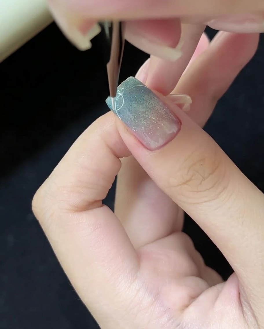 세필 브러쉬와 화이트 젤로 손톱 끝에 가는 곡선을 그리는 모습.