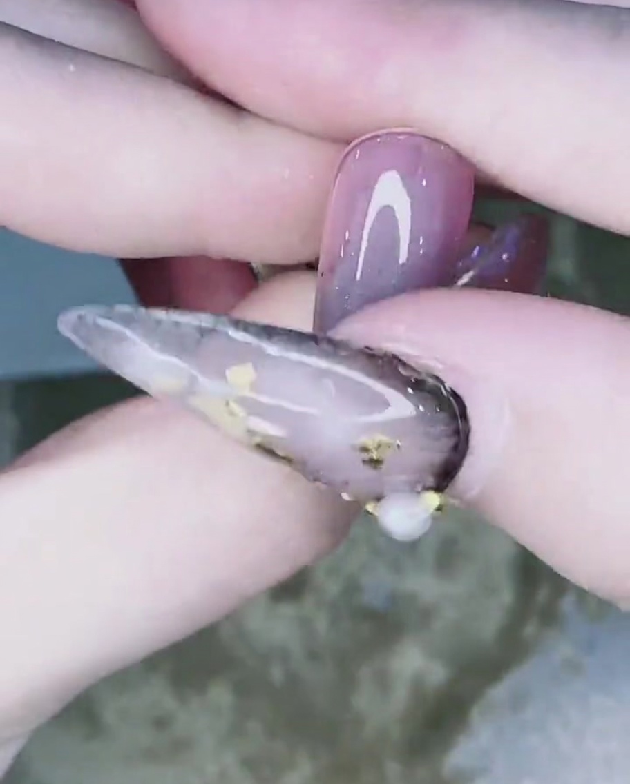 손톱 끝부터 위쪽으로 크롬 파우더를 블렌딩하여 그라데이션을 만드는 손가락.