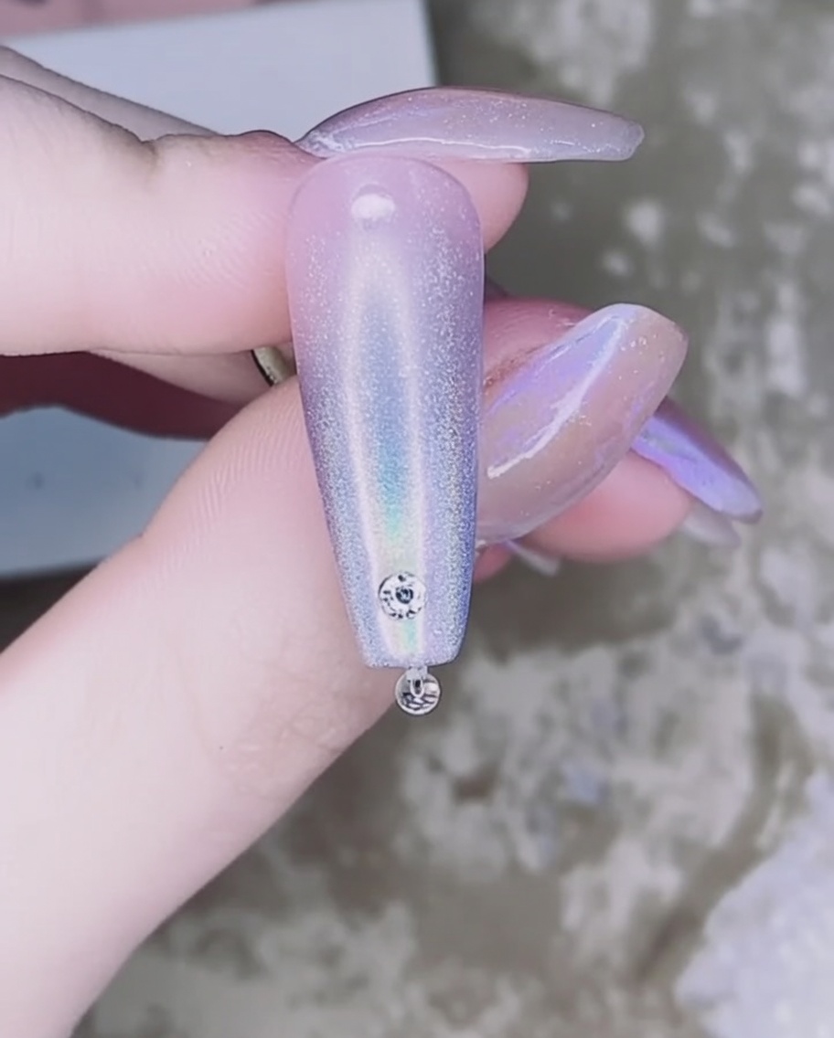핀셋으로 작고 투명한 라인스톤을 집어 네일 위의 접착 젤 위에 올리는 모습.