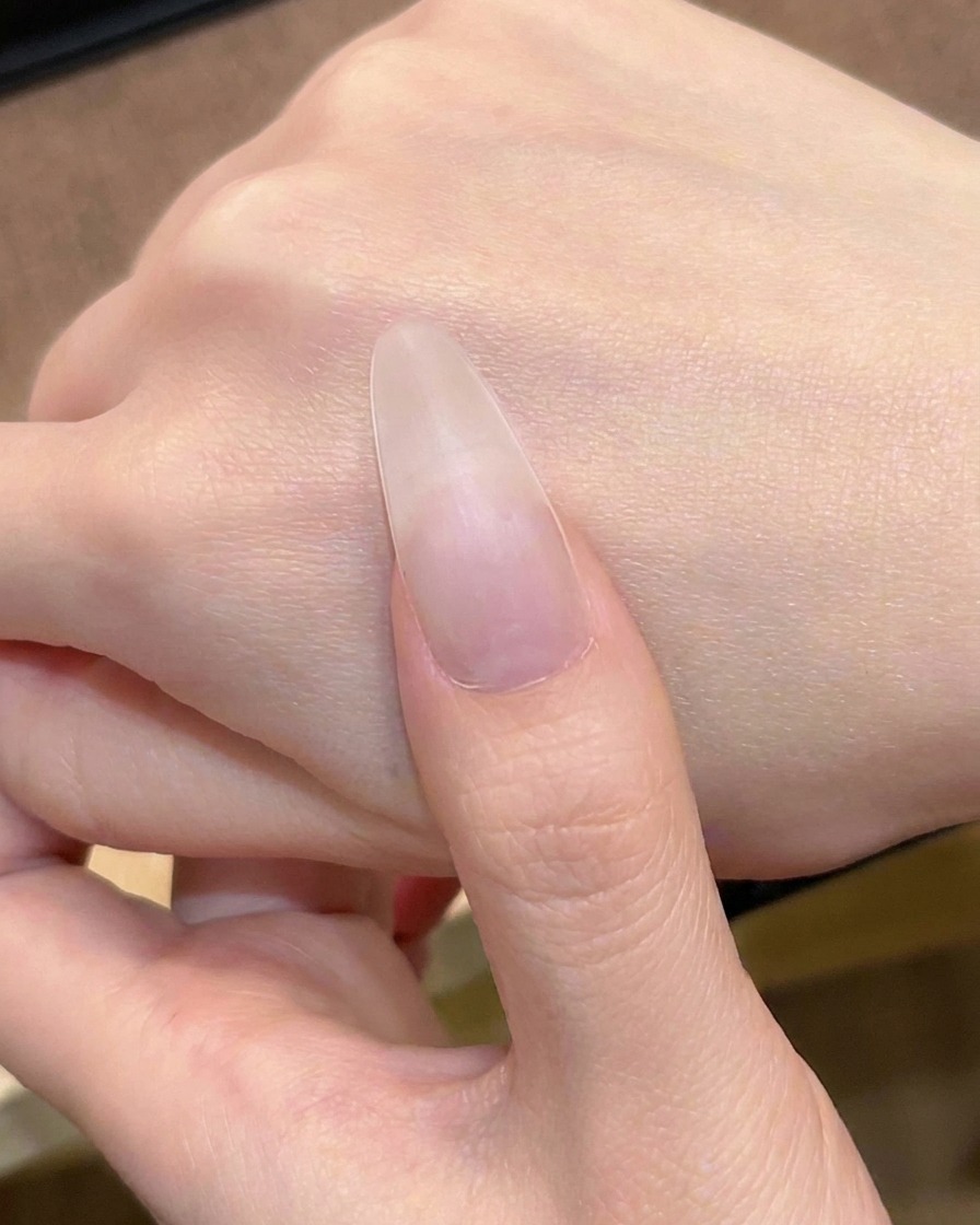네일 브러시로 투명한 누드 핑크 젤을 첫 번째 레이어로 바르는 모습.