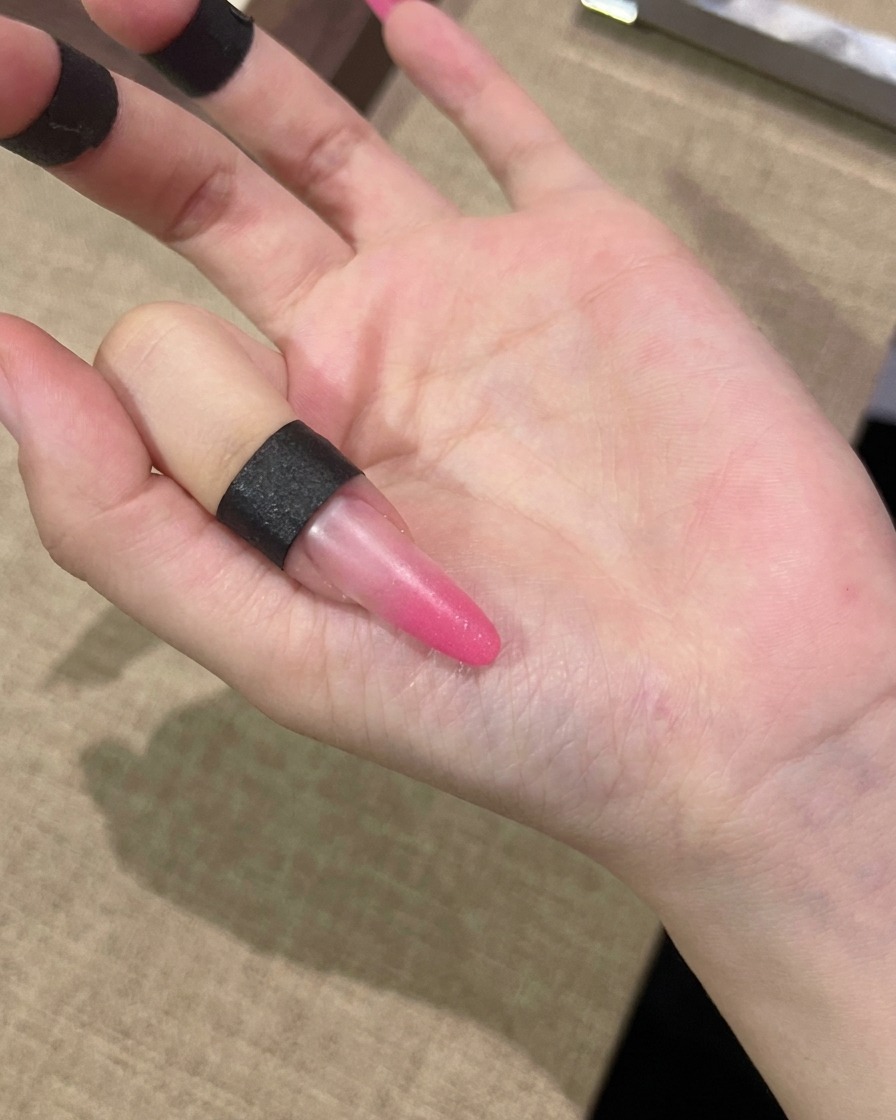 손톱 전체에 핑크색 캣츠아이 젤을 브러시로 펴 바르는 모습.