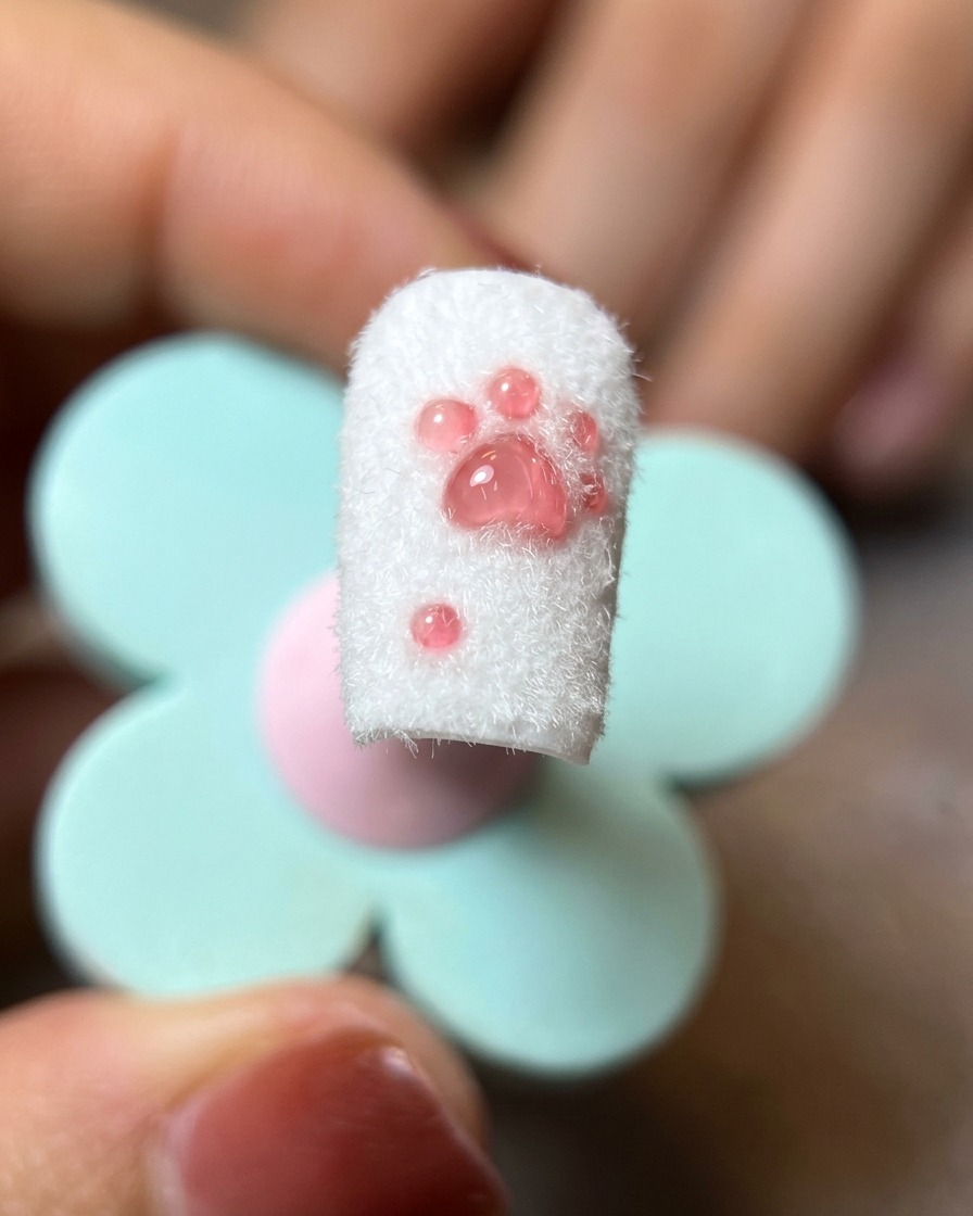 완성된 고양이 발바닥 네일 디자인의 잔여 파우더를 부드러운 브러시로 털어내는 모습.