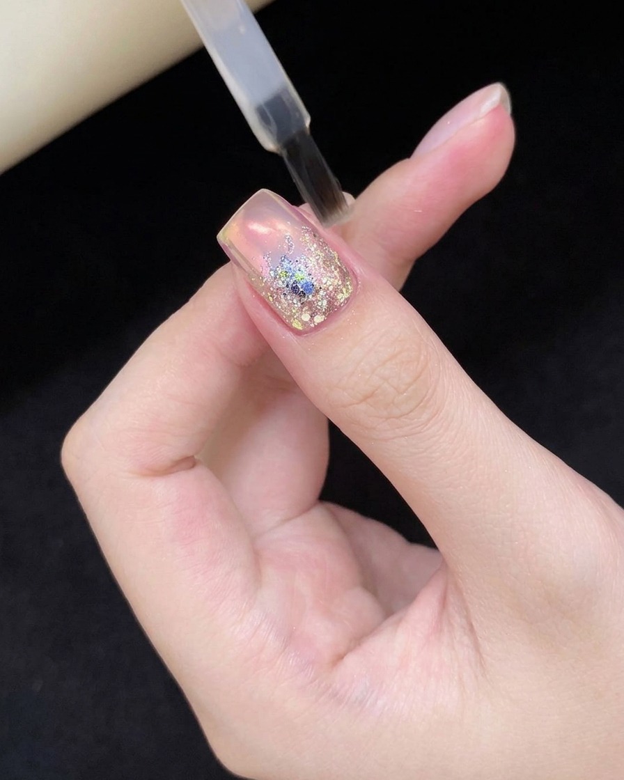 글리터 네일 아트가 완성된 손가락을 전문가용 UV/LED 램프 안에 넣고 큐어링하는 모습.