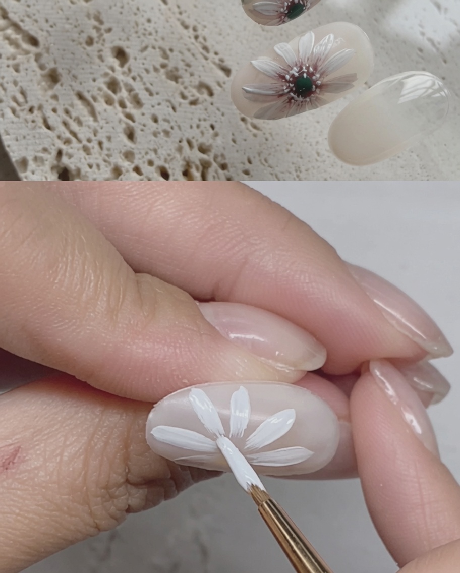 완성된 데이지 디자인 위에 투명 탑 코트를 바르는 근접 사진.