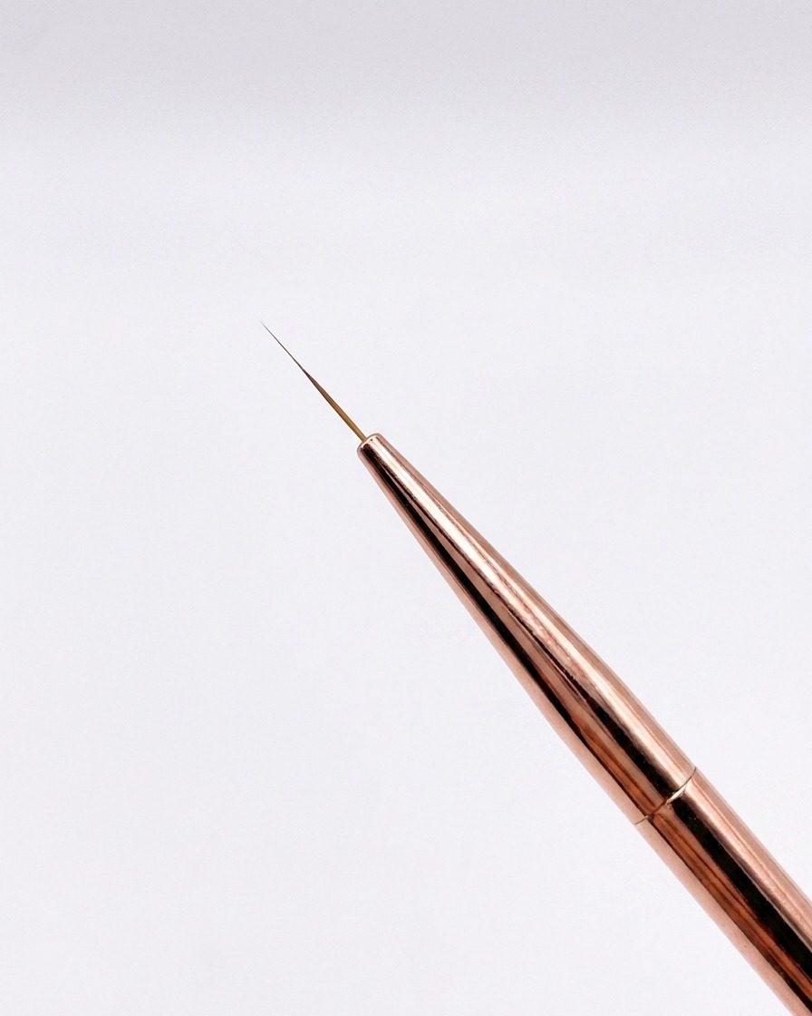 중립적인 배경을 바탕으로 끝이 날렵하게 모인 미세한 12mm 로즈골드 라이너 브러시의 근접 샷.
