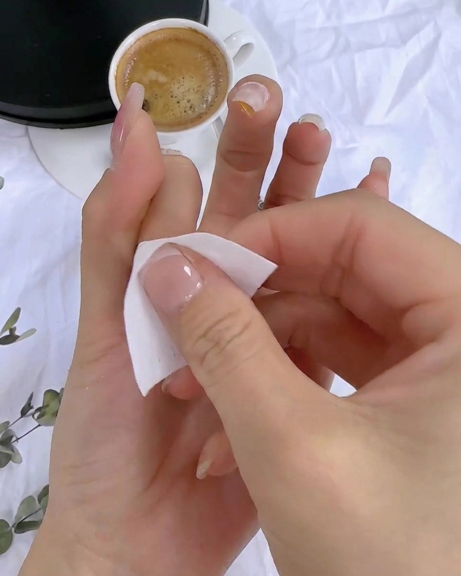 큐어링된 네일 표면의 끈적이는 잔여물을 보풀 없는 와이프로 닦아내는 모습.