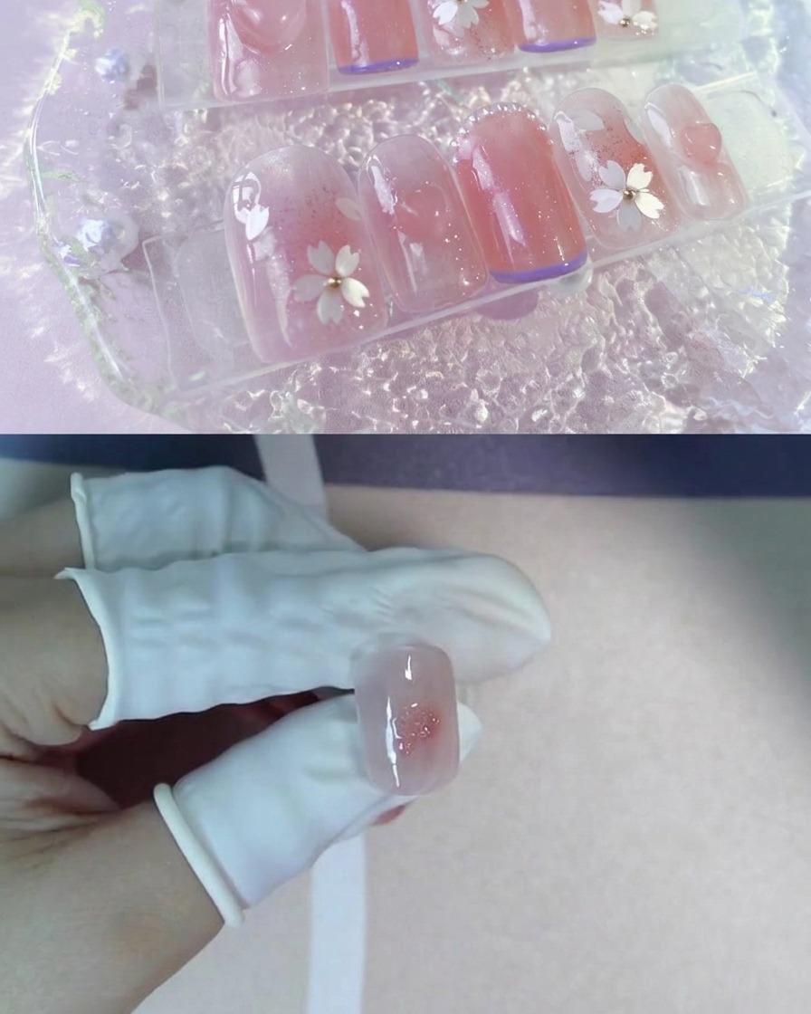 핑크빛 블러셔 중앙에 반짝이는 젤이 점찍힌 인조 네일 팁을 든 장갑 낀 손가락.