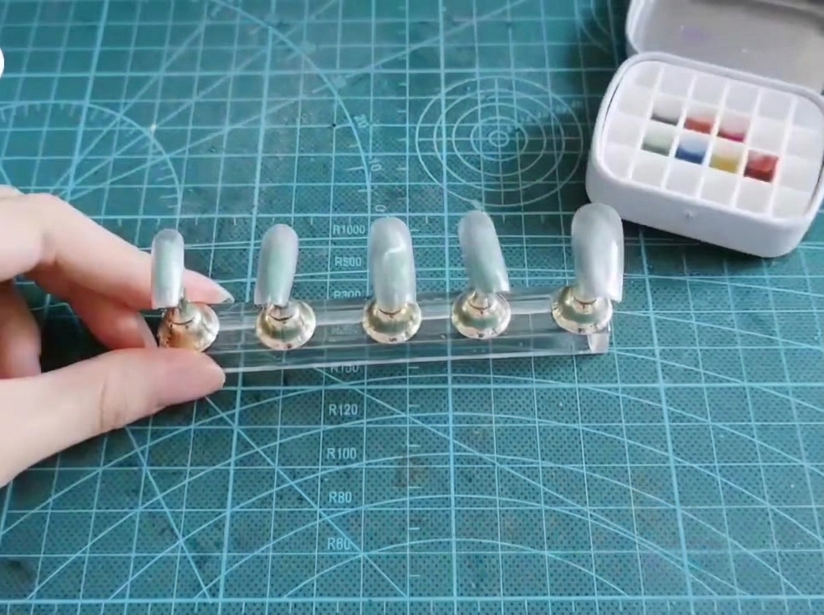 멀티 웰 젤 팔레트에서 플랫 네일 브러시가 블루와 퍼플 피그먼트를 묻히는 모습.