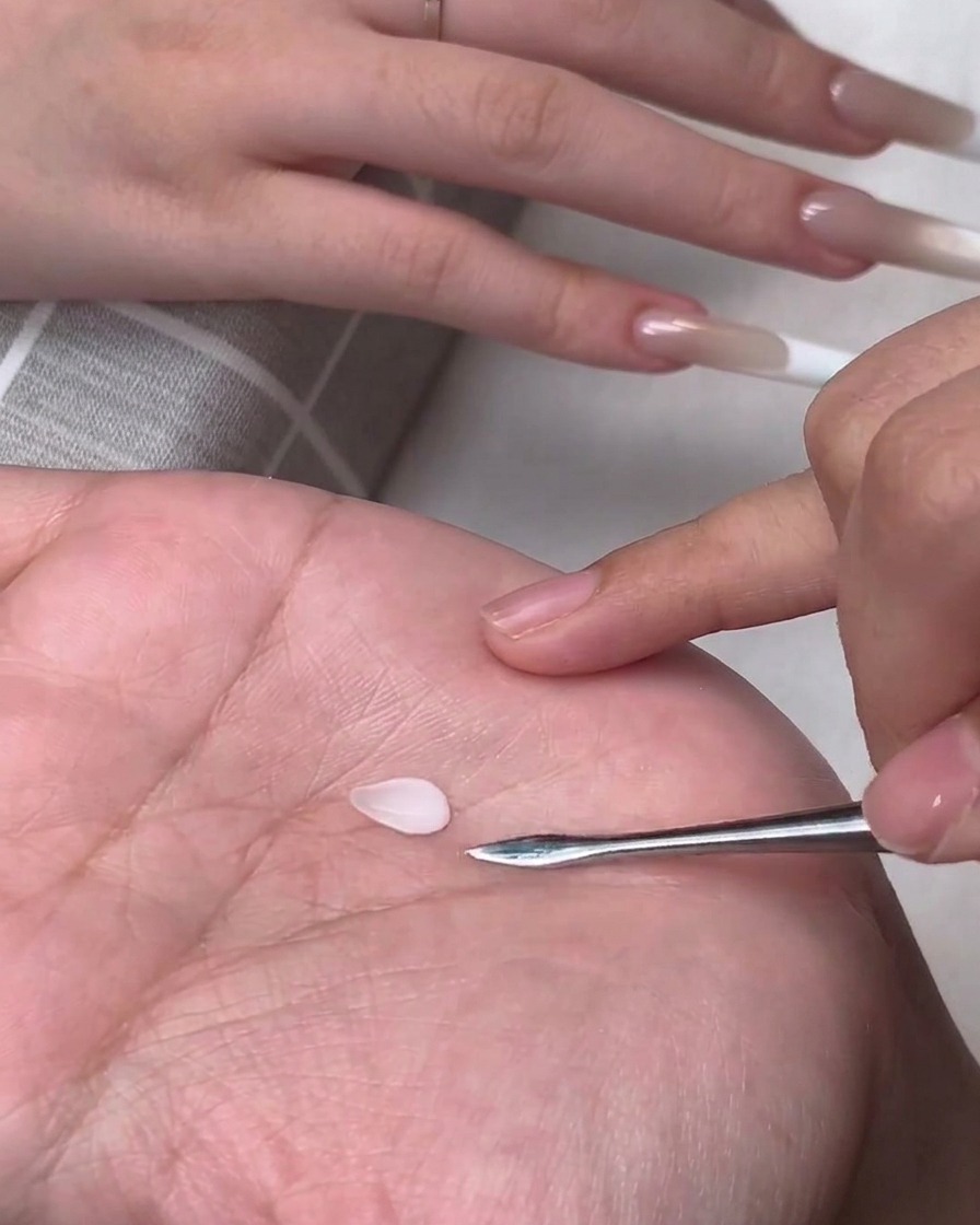 금속 카빙 툴 옆에 작고 물방울 모양의 화이트 3D 젤 꽃잎이 손바닥 위에 놓여 있는 모습.