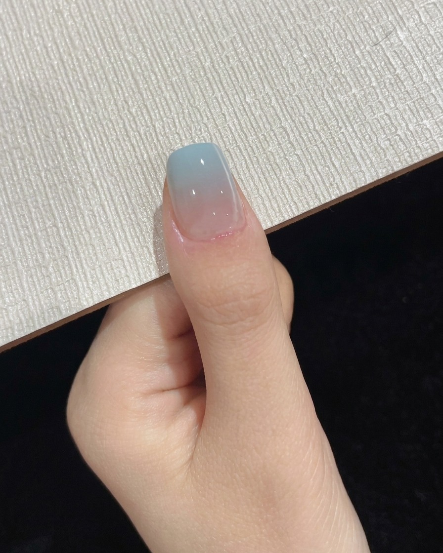 최종 탑코트 경화 단계에서 휴대용 UV LED 램프 아래에 위치한 엄지손가락.