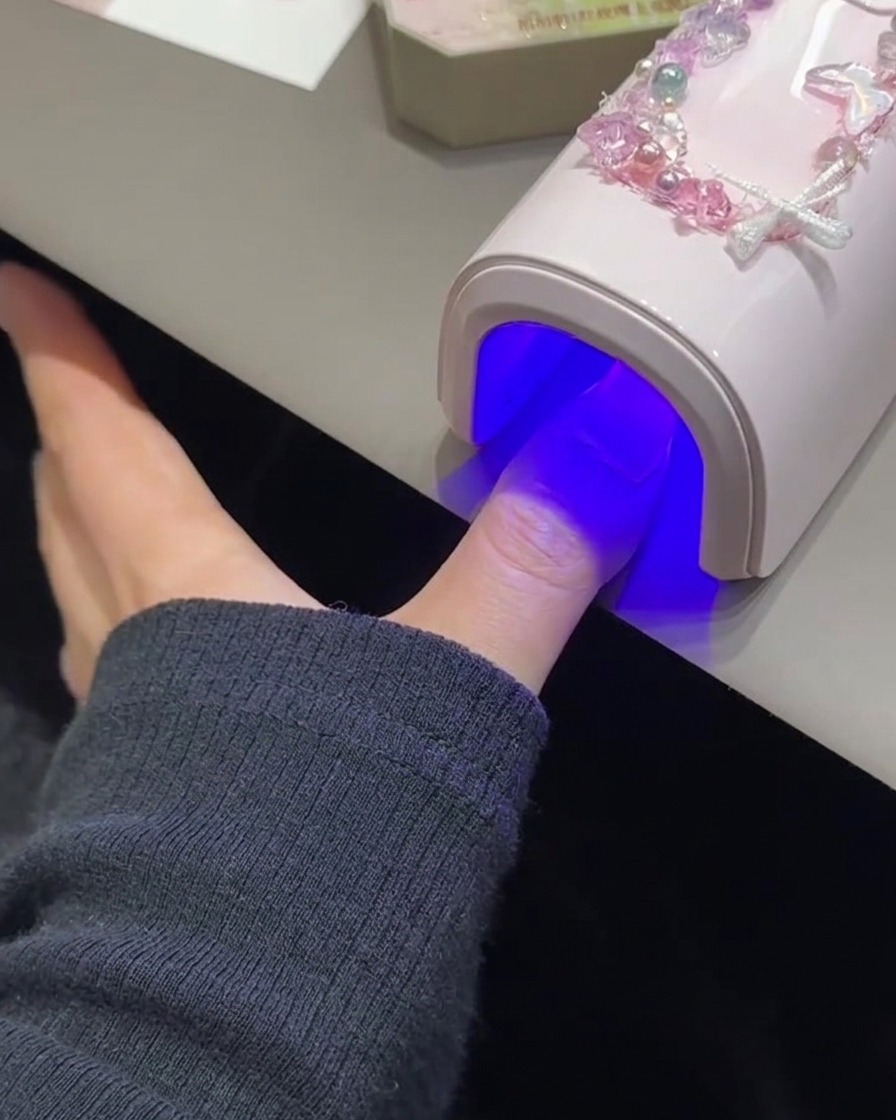 핑크빛 UV/LED 램프 아래에서 손톱이 큐어링되는 모습.