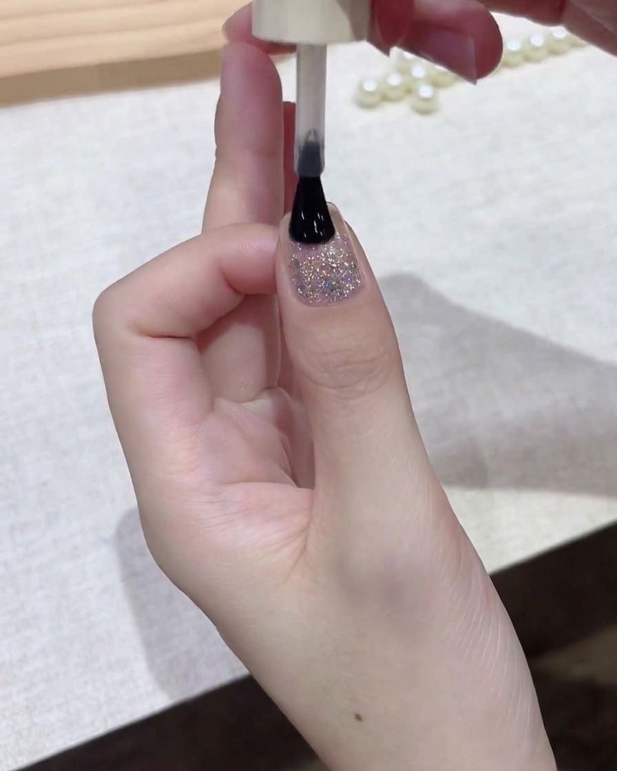 폴리시 브러시가 네일 표면 전체에 다크 젤 폴리시를 얇게 펴 바르는 모습.