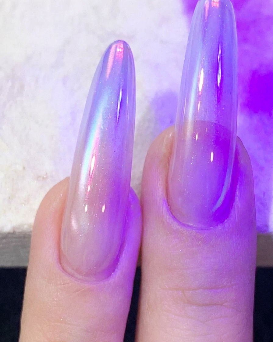 자줏빛 UV/LED 네일 램프 아래에서 캣츠아이 젤을 큐어링하는 손가락.