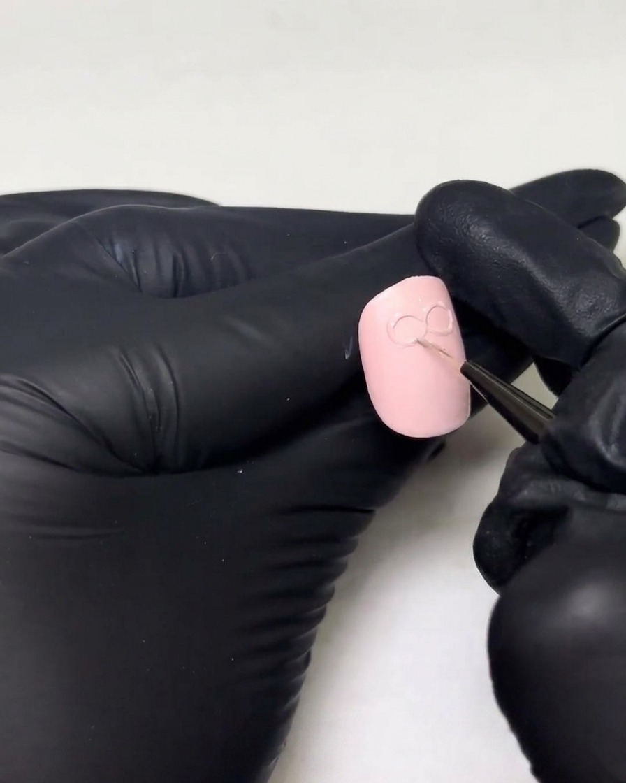장갑을 낀 손이 손톱에 그려진 3D 리본 디자인의 기존 루프 위에 두꺼운 층의 빌더 젤을 더하는 모습.