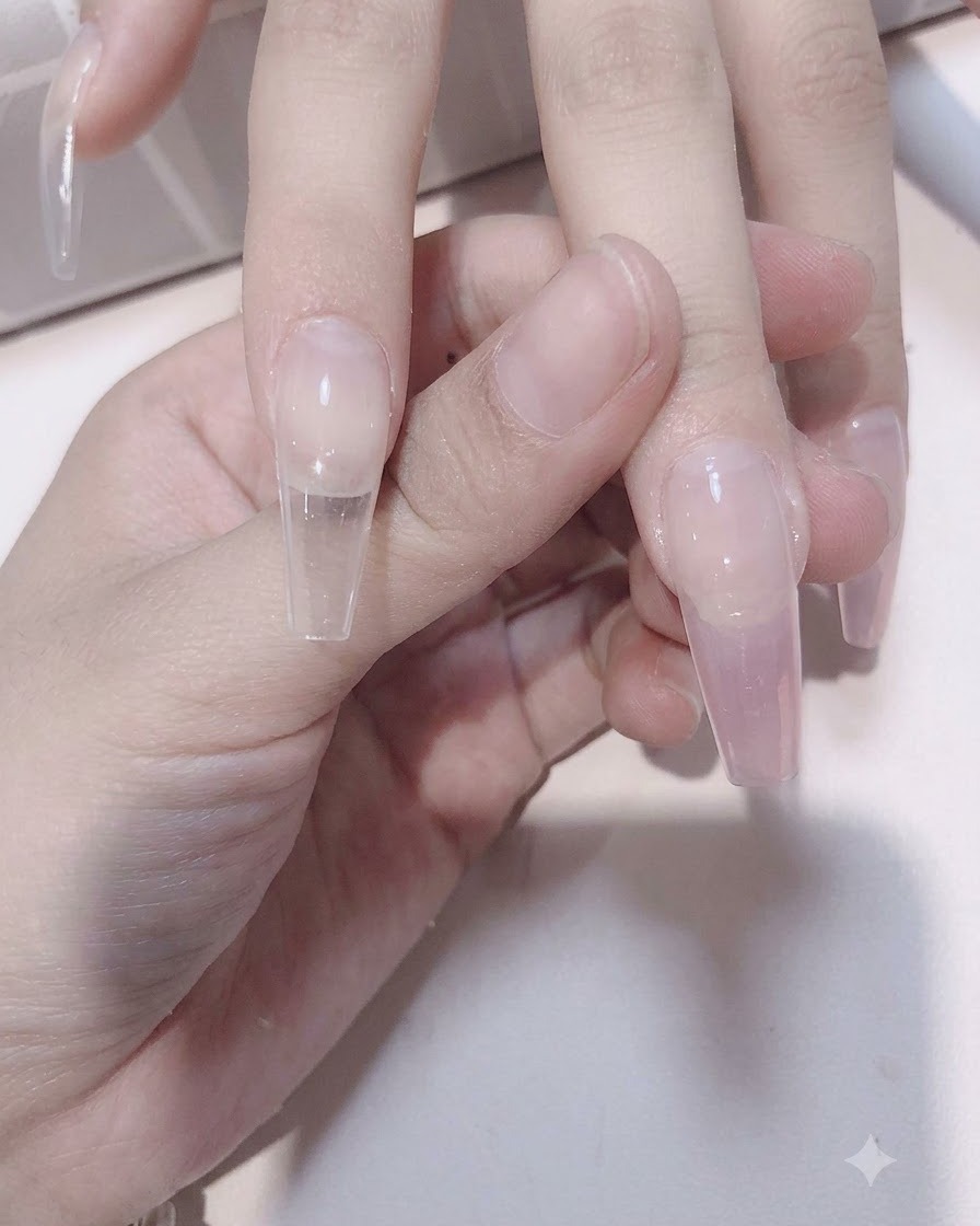 투명한 네일 연장 팁 위로 시어 핑크 젤을 아래쪽으로 쓸어내리며 그라데이션 효과를 내는 네일 브러시.