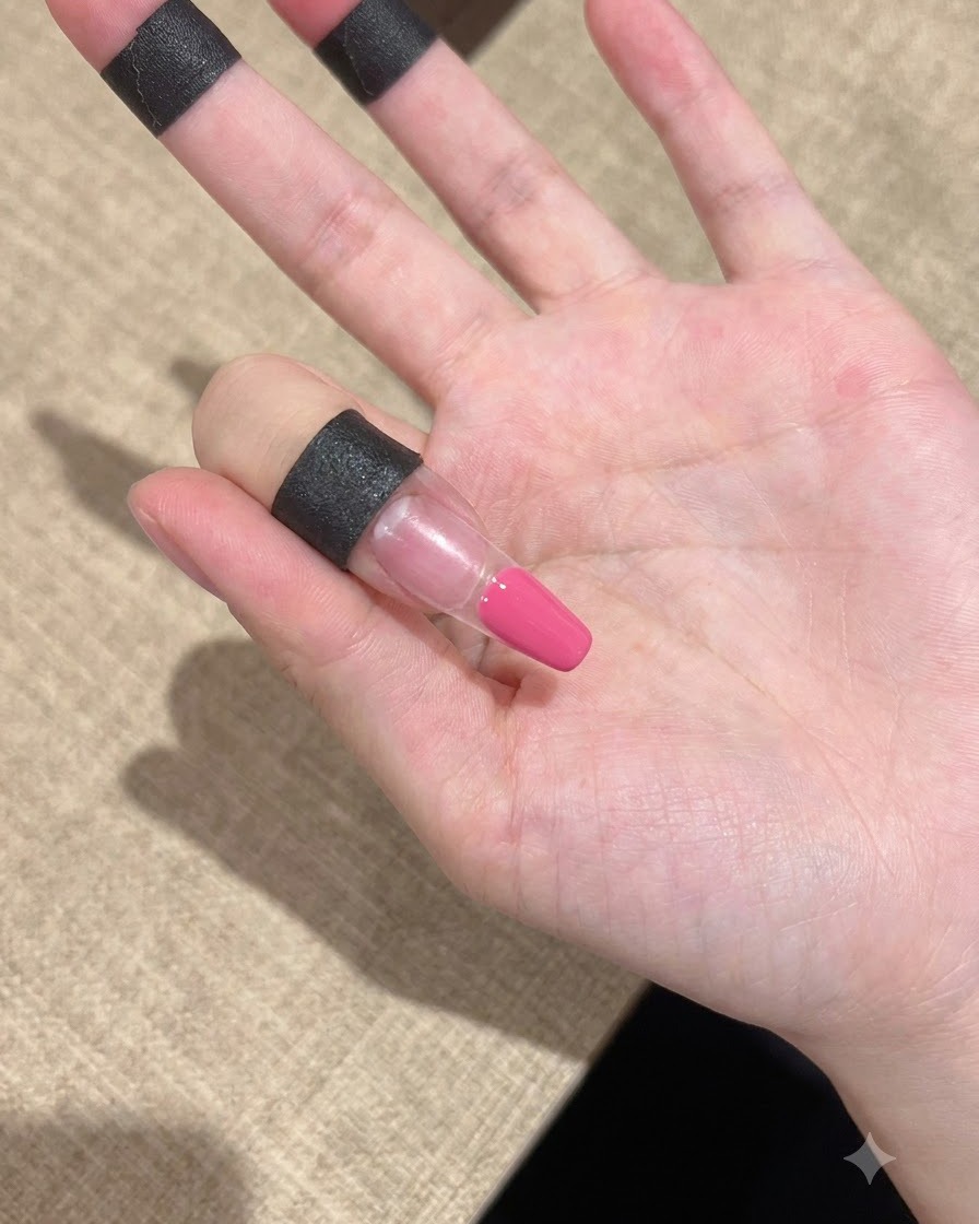 손톱 끝부분에 핑크빛 젤이 깔끔하게 발려 있는 손가락의 클로즈업 샷.