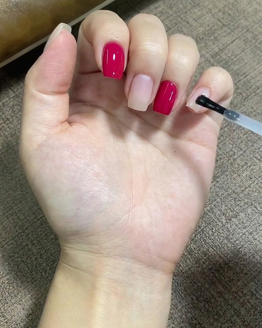 브러시를 이용해 손톱 표면 전체에 투명한 베이스 코트를 고르게 펴 바르는 모습.