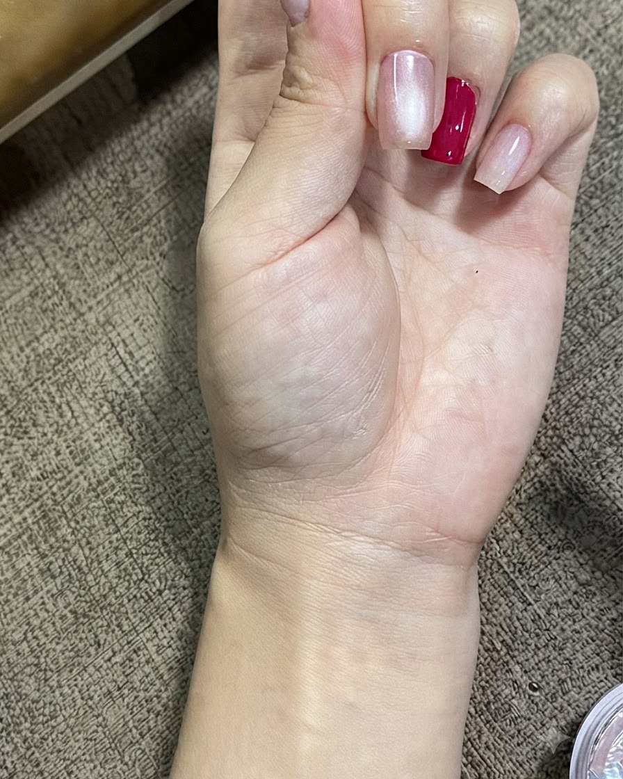 마그네틱 캣아이 젤로 처리된 손톱에서 빛나는 구체 효과를 보여주는 손의 클로즈업 뷰.