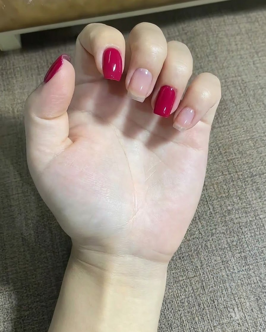 파인 라이너 브러시를 사용하여 가운데 손가락의 별 디자인 근처에 작은 레드 도트를 찍고 있는 손의 클로즈업.