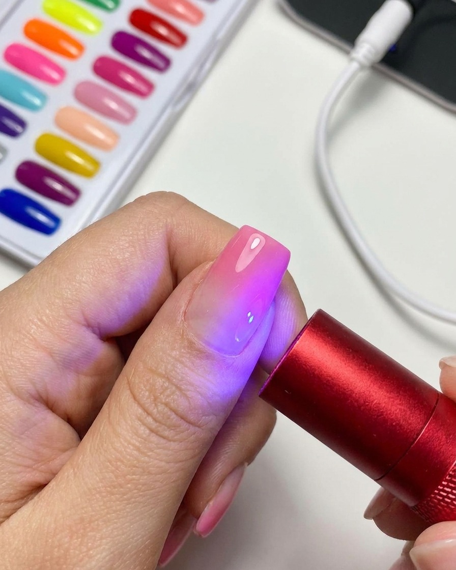 휴대용 레드 UV/LED 큐어링 램프가 완성된 마그네틱 캣아이 젤 네일을 비추며 빛나는 모습.