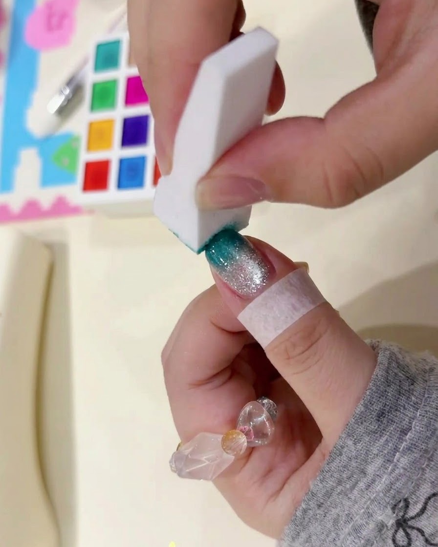 다크 틸 그라데이션을 짙게 만들기 위해 네일 팁 부분을 하얀 스펀지 블록으로 가볍게 두드리는 모습입니다.