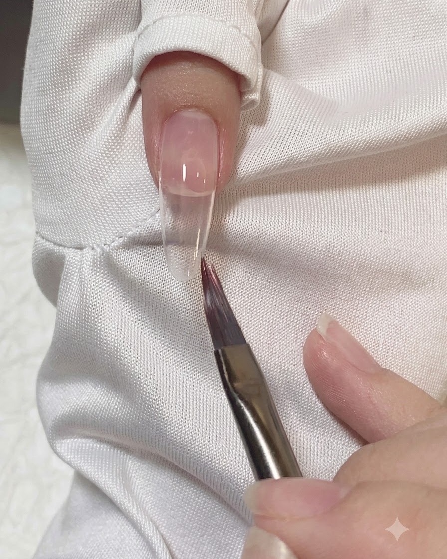 네일에 바른 핑크 젤의 경계를 부드럽게 펴 바르고 다듬는 플랫 브러시.