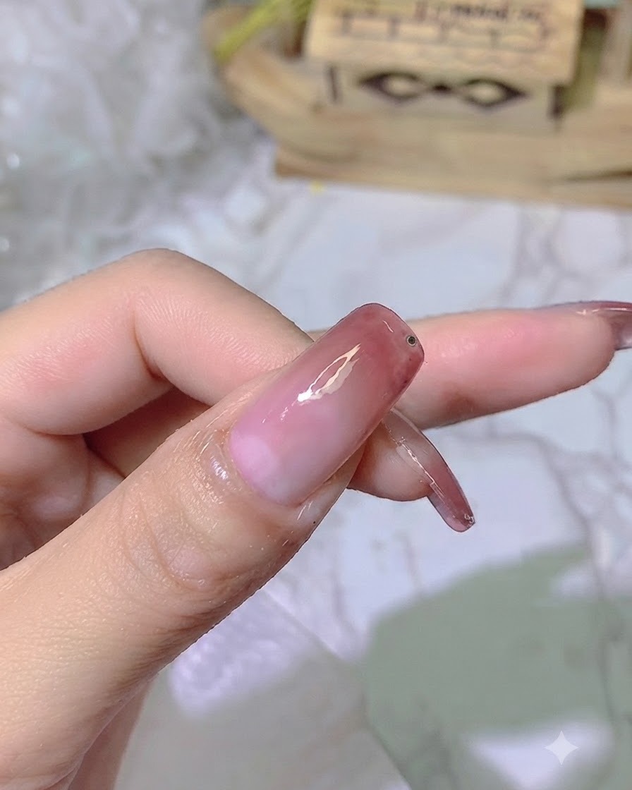 완성된 그라데이션 네일의 끝부분 근처에 투명한 접착 젤 방울이 얹혀 있는 모습.