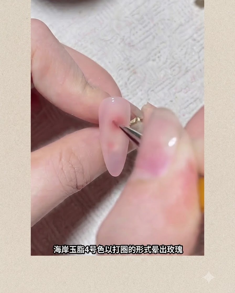 파인 디테일 브러시가 핑크 젤이 코팅된 손톱 위에 붉은색 원형 피그먼트 점을 그려 꽃이 퍼져나가는 모양을 만드는 모습.