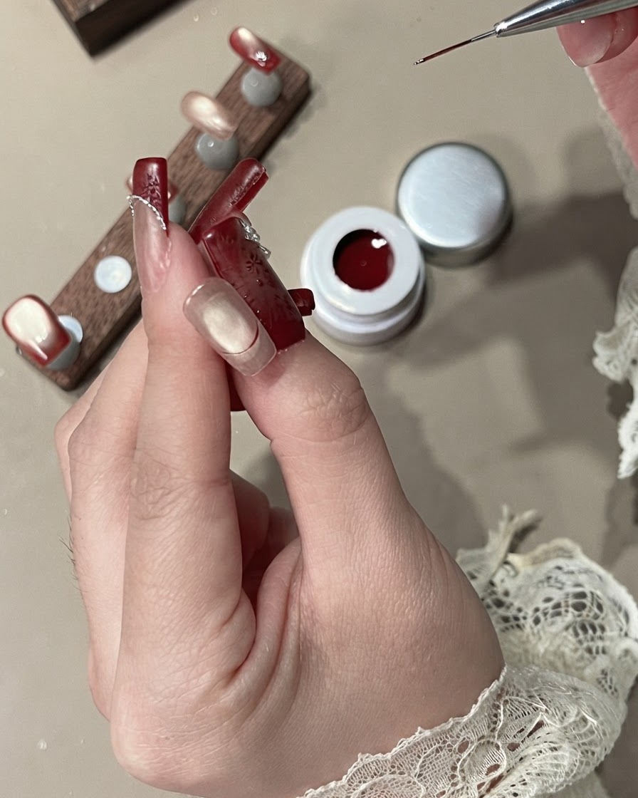 라이너 브러시로 불투명한 레드 벨벳 젤을 사용하여 프렌치 팁 영역을 채우는 모습.