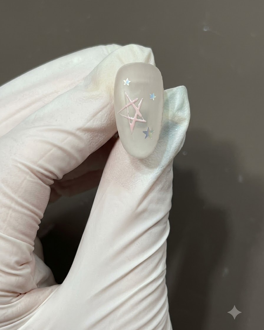 무광 네일 위에 그려진 별 아웃라인 안쪽을 연한 핑크 젤 폴리시로 세필 네일 브러시를 이용해 채우는 모습.