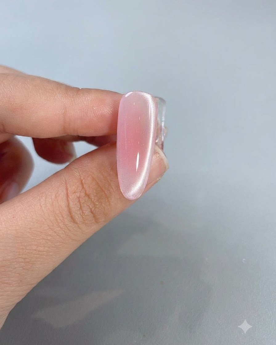 측면을 따라 흐르는 밝은 빛 반사 라인이 돋보이는 완성된 핑크 캣아이 네일의 클로즈업 샷.