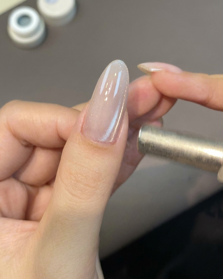 작은 자석 도구를 손톱 가까이 대어 자석 젤 입자를 활성화하는 모습.