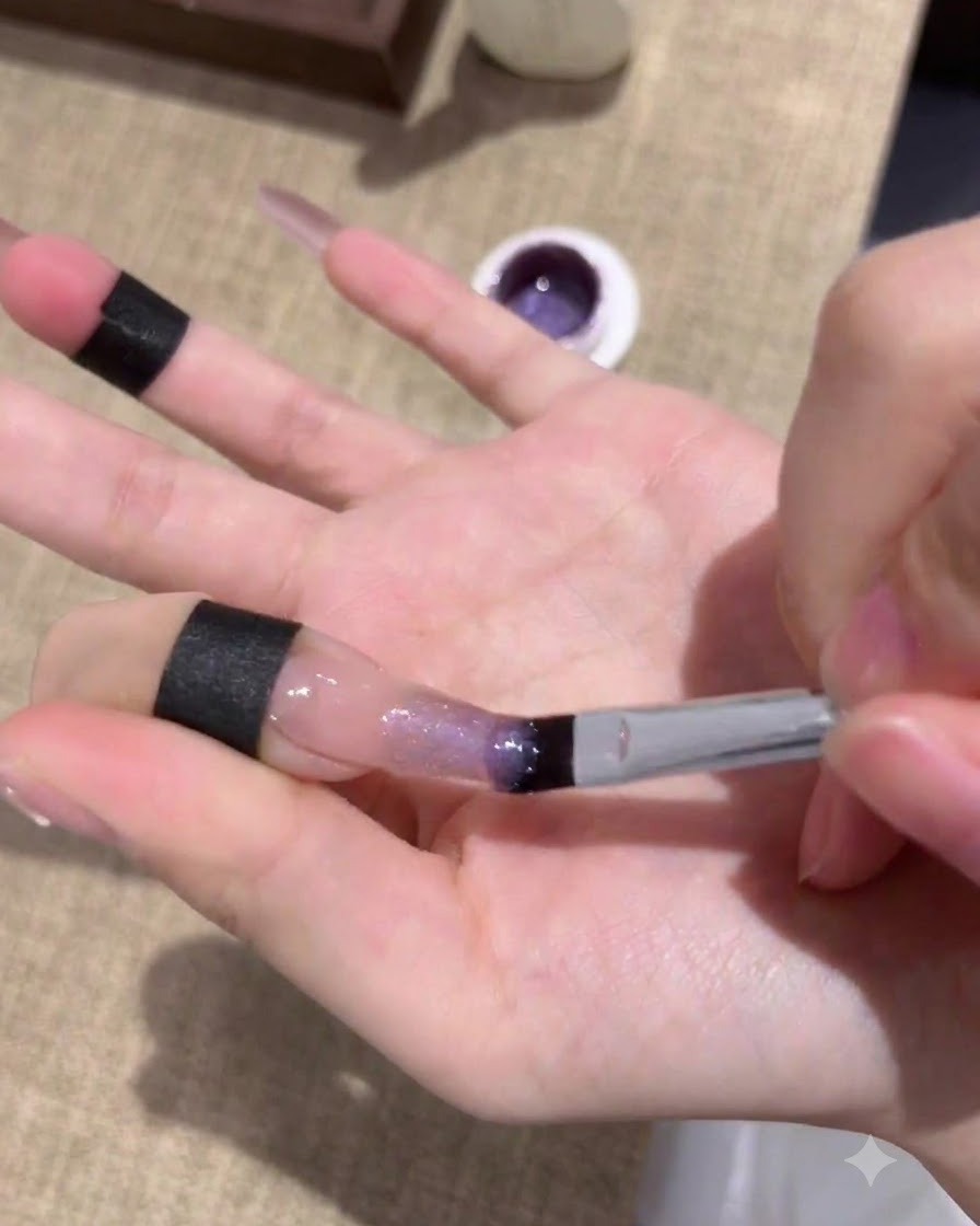 첫 번째 퍼플 캣아이 젤 도포 후 UV/LED 램프 아래에서 경화 중인 네일.