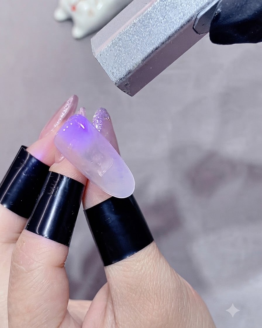 손가락을 미니 UV/LED 램프 아래에 넣어 블렌딩된 컬러 층을 경화하는 모습.