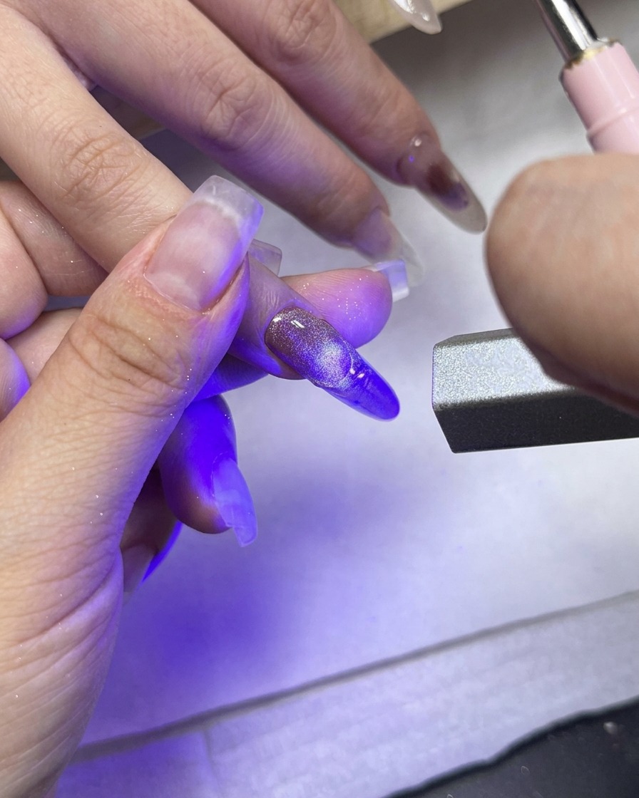 텍스처 프렌치 팁이 돋보이는 가운데 손가락을 향해 직접 비추는 UV/LED 큐어링 라이트.