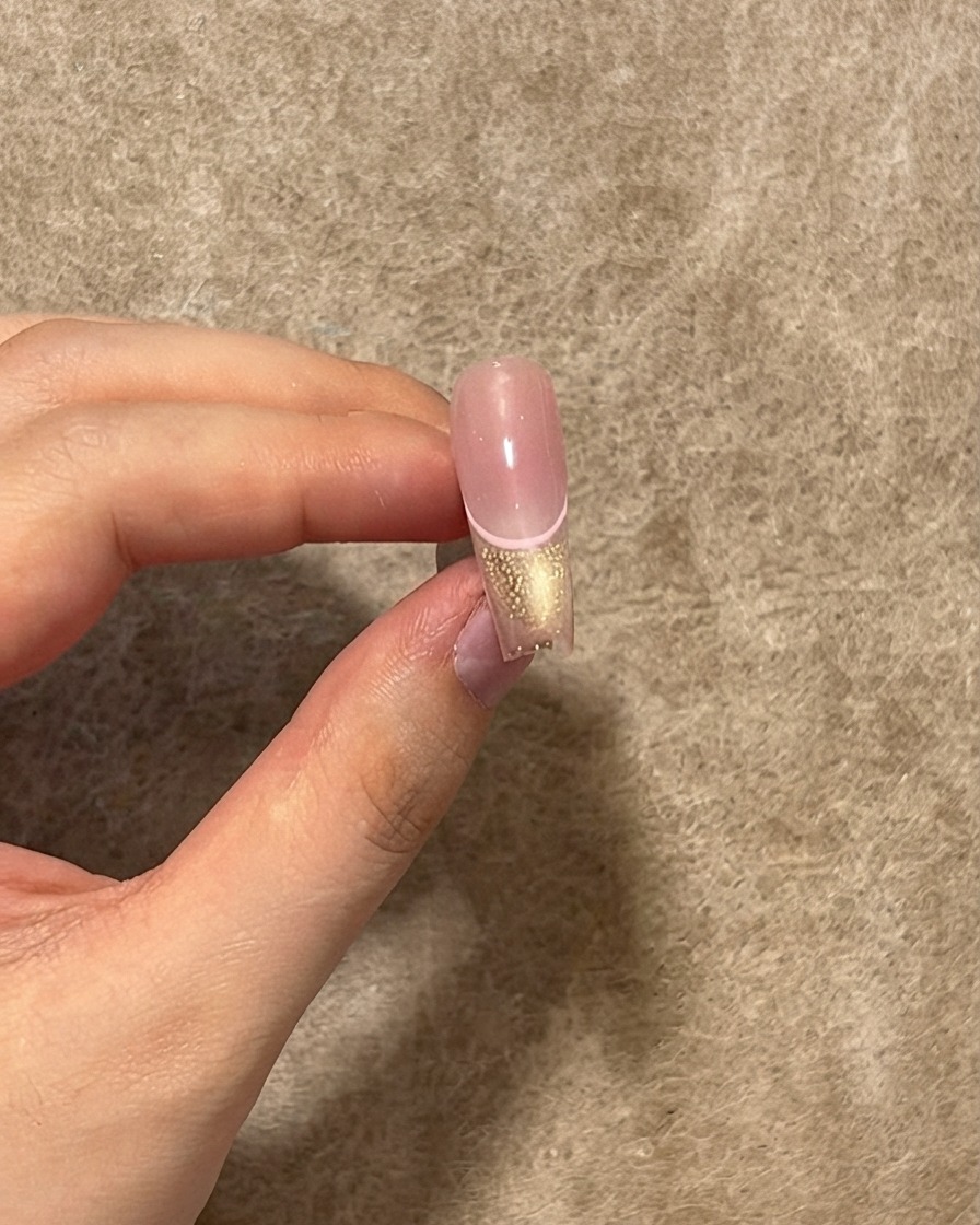 핑크 라인, 캣아이 팁, 블러시 센터 위에 광택 있는 탑 코트 레이어가 발라진 완성된 네일의 모습.