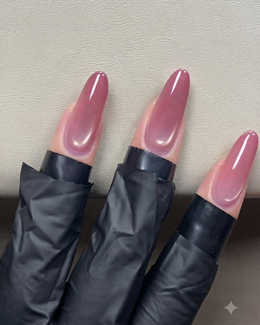 네일 브러시가 아몬드 셰이프의 자석 네일 위로 클리어 탑 코트를 부드럽게 쓸어내리며 광택을 내는 모습.