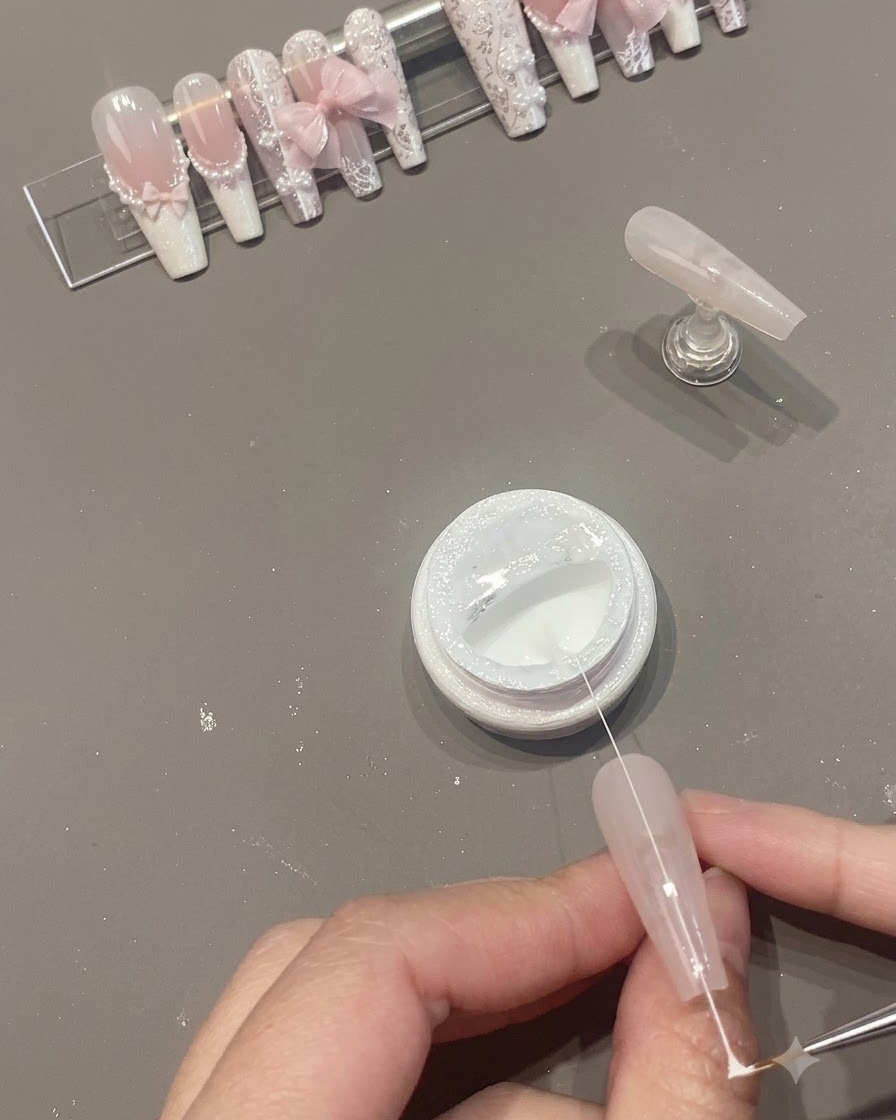 오픈된 젤 병 위에서 네일 표면을 가로지르는 가늘고 하얀 거미줄 젤 실.