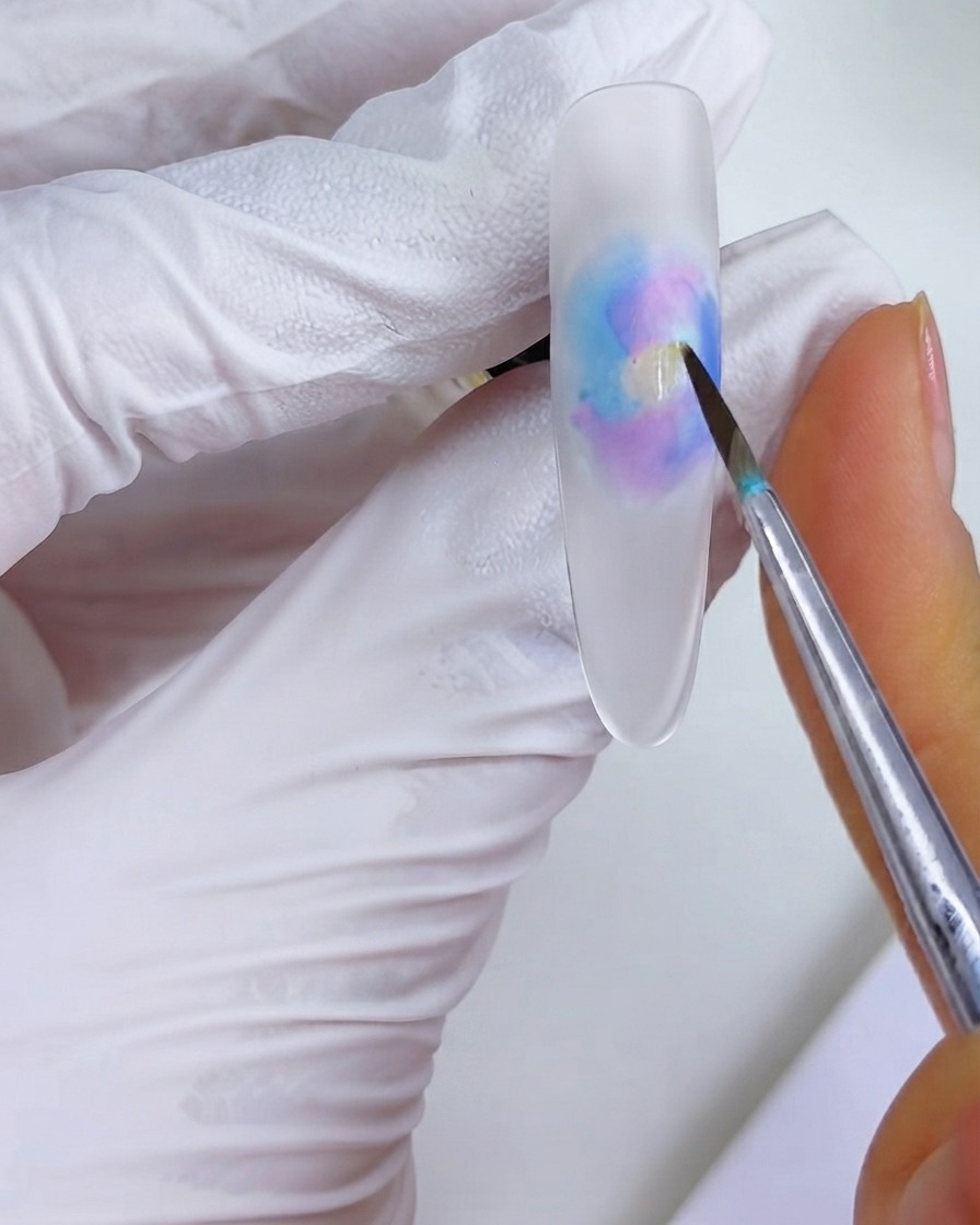 세필 브러시로 수채화 블룸 패턴 한가운데 오렌지 잉크 방울을 얹는 모습.
