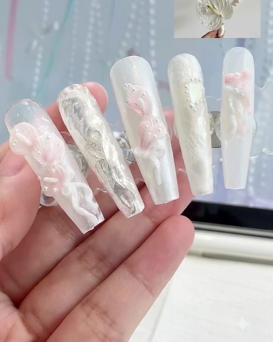 다양한 3D 화이트 및 핑크 플로럴 네일 아트 디자인이 부착된 프레스온 네일 디스플레이 스탠드.