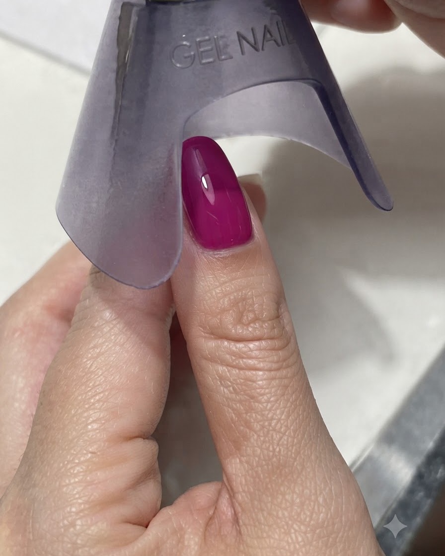 보라색 핸드헬드 UV/LED 램프가 밝은 빛 아래에서 생동감 넘치는 진한 마젠타 또는 블루 네일을 경화하는 모습.