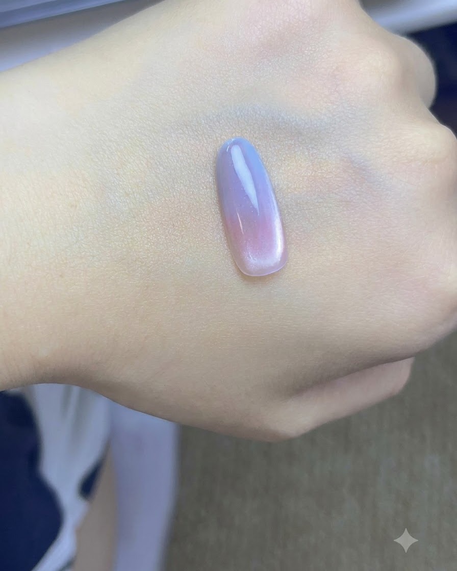 손 위에 놓인 네일 팁에 브러시로 두 번째 블루 젤 레이어를 두드려 바르는 모습.