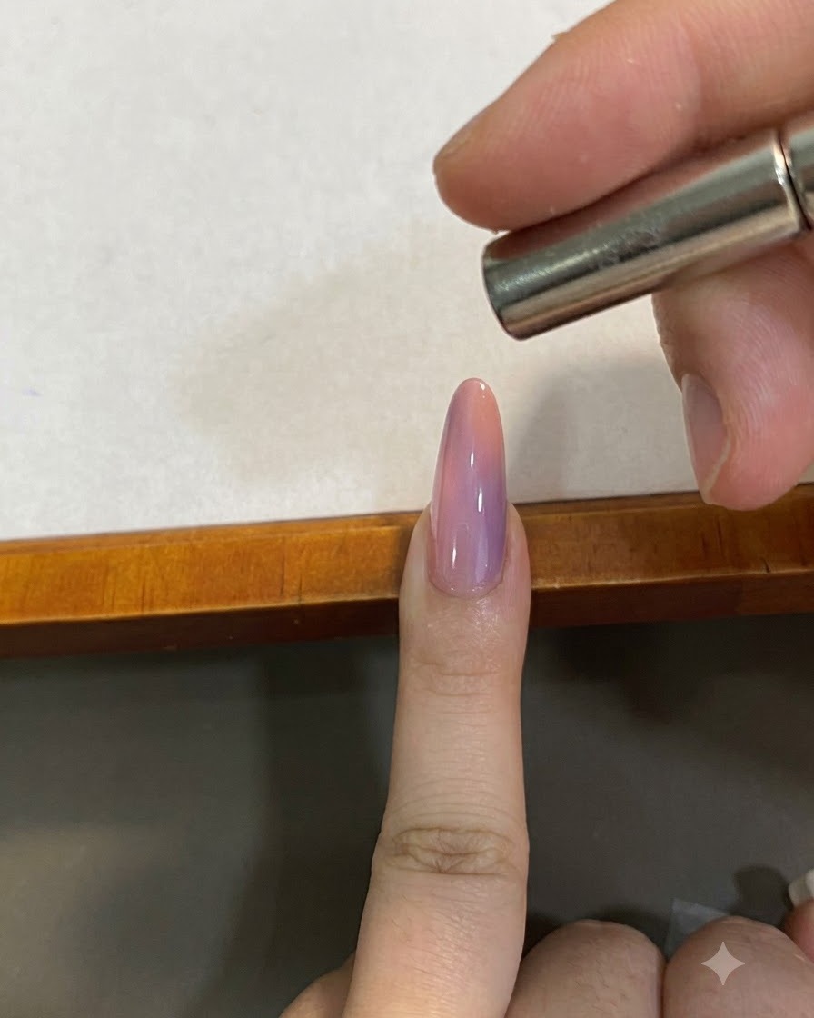 핑크 그라데이션 자석젤 네일 바로 위에서 자석 피그먼트를 모양내기 위해 작은 자석을 가까이 댄 모습.