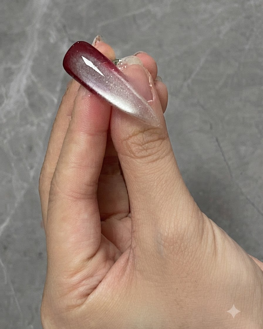 경화 램프 아래에 위치한 그라데이션 및 캣아이 네일 디자인이 있는 손가락.