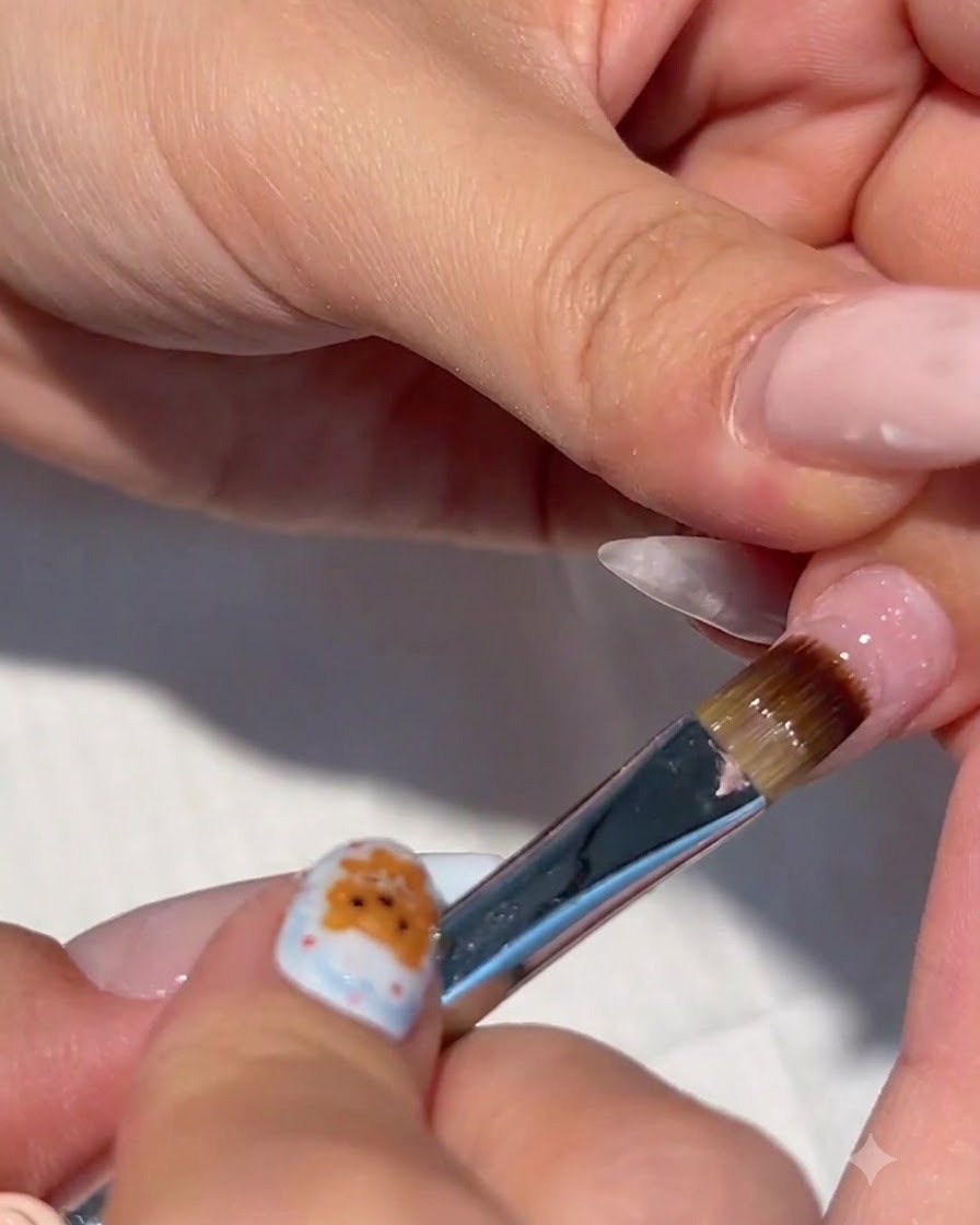 Eine Nahaufnahme eines Nagelpinsels, der klares Builder Gel auf einen vorbereiteten Fingernagel aufträgt.