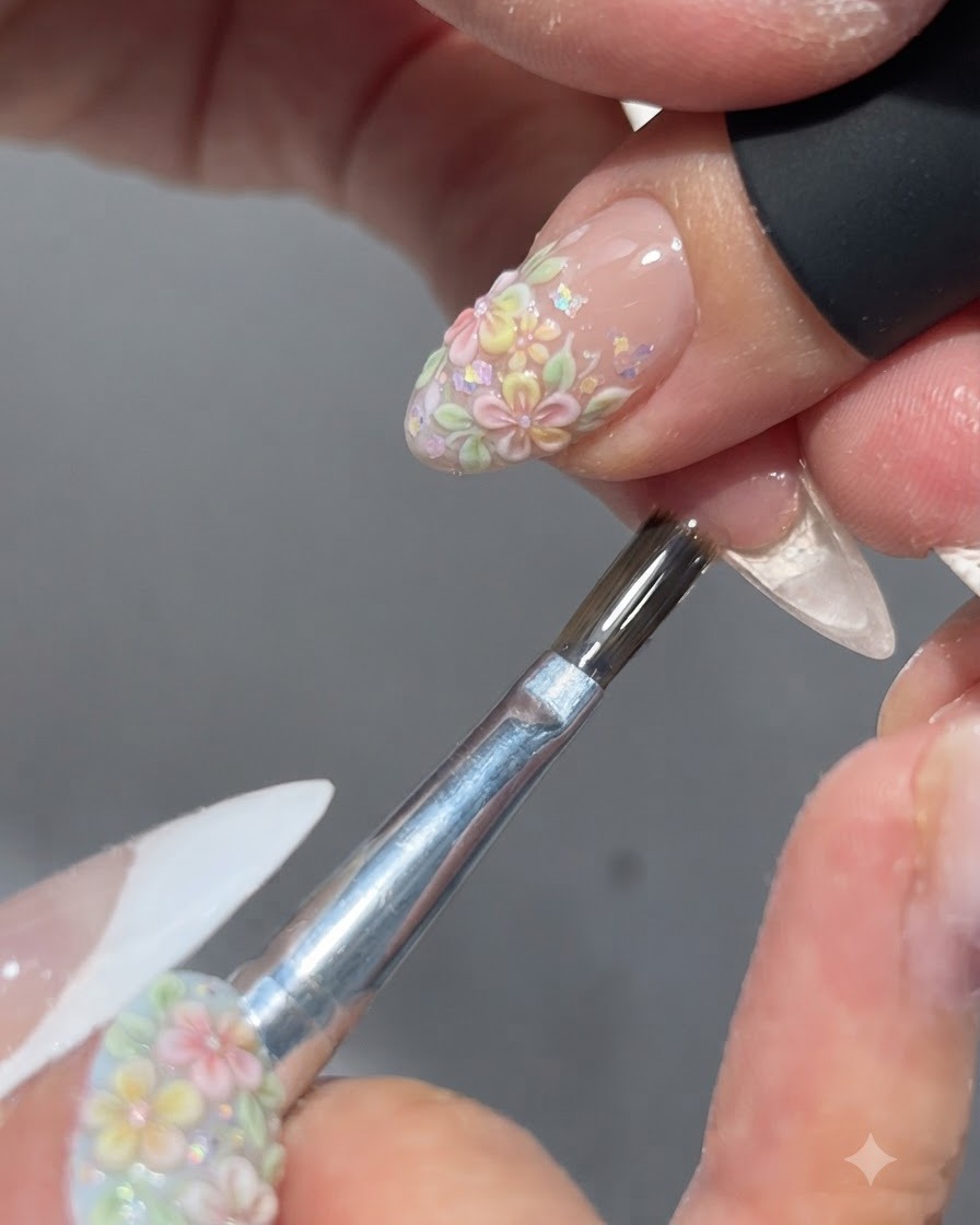 Ein Pinsel trägt einen glänzenden Top Coat über ein fertiges Blumen-Nageldesign auf.
