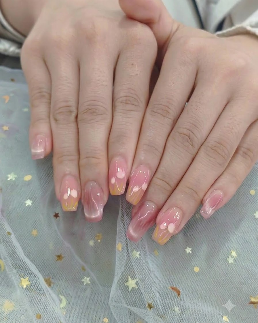 완성된 하트 및 그라데이션 네일 디자인 전체에 브러시로 글로시 탑 코트를 쓸어내리는 모습.
